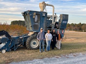 Students standing in a field in front of farming equipment